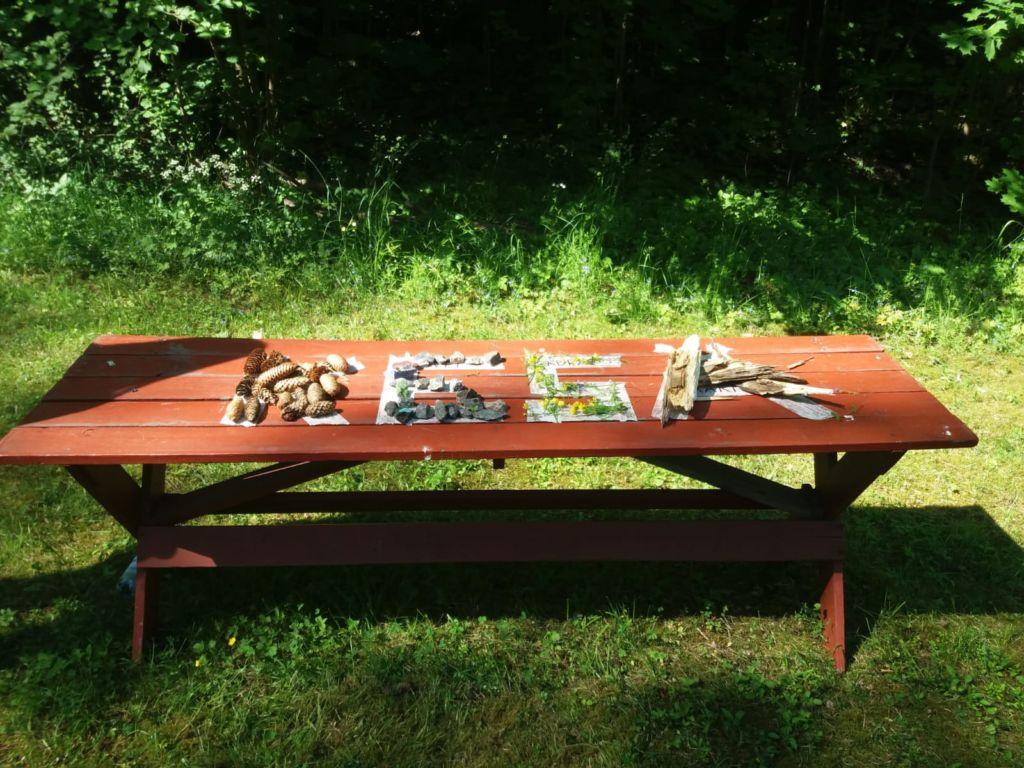 Pöytä, jossa erilaisista esineistä on muotoiltu sana kesä