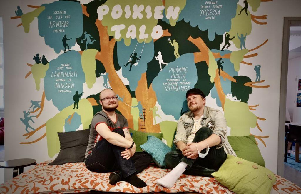Kuvassa värikkään seinän edustalla istuu sohvalla kaksi henkilöä