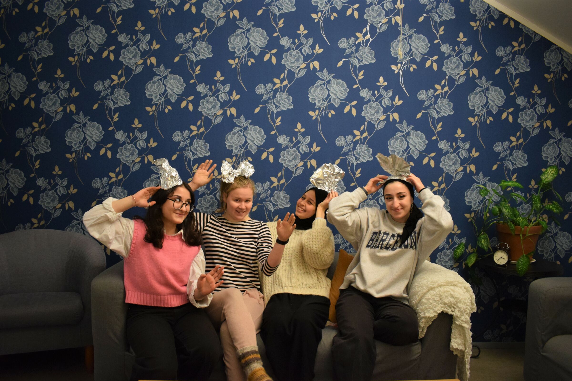 Eri näköisiä tyttöjä istumassa ja hymyilemässä sohvalla sinisessä huoneessa